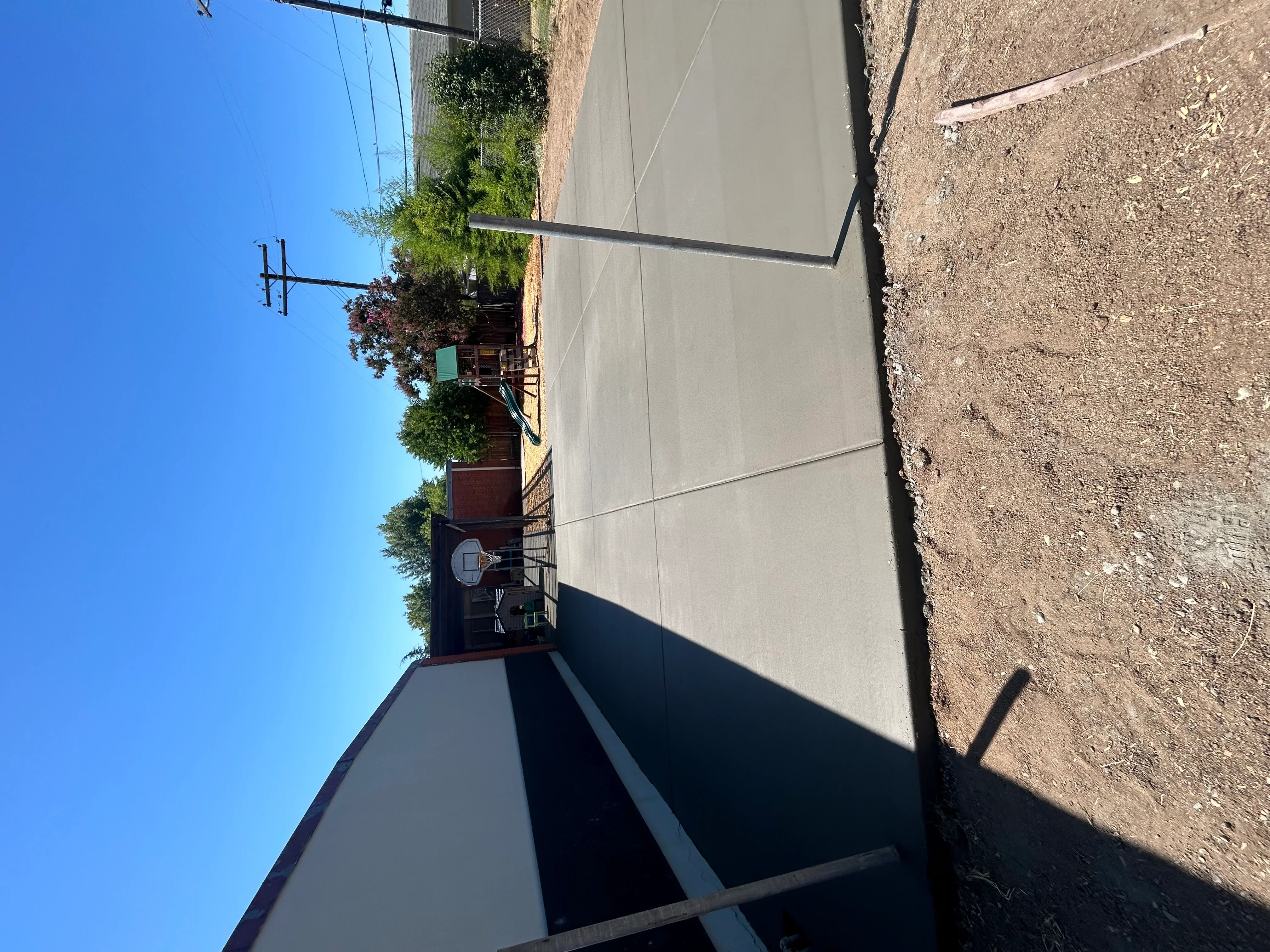 New concrete driveway and walkway alongside brick home with landscaping