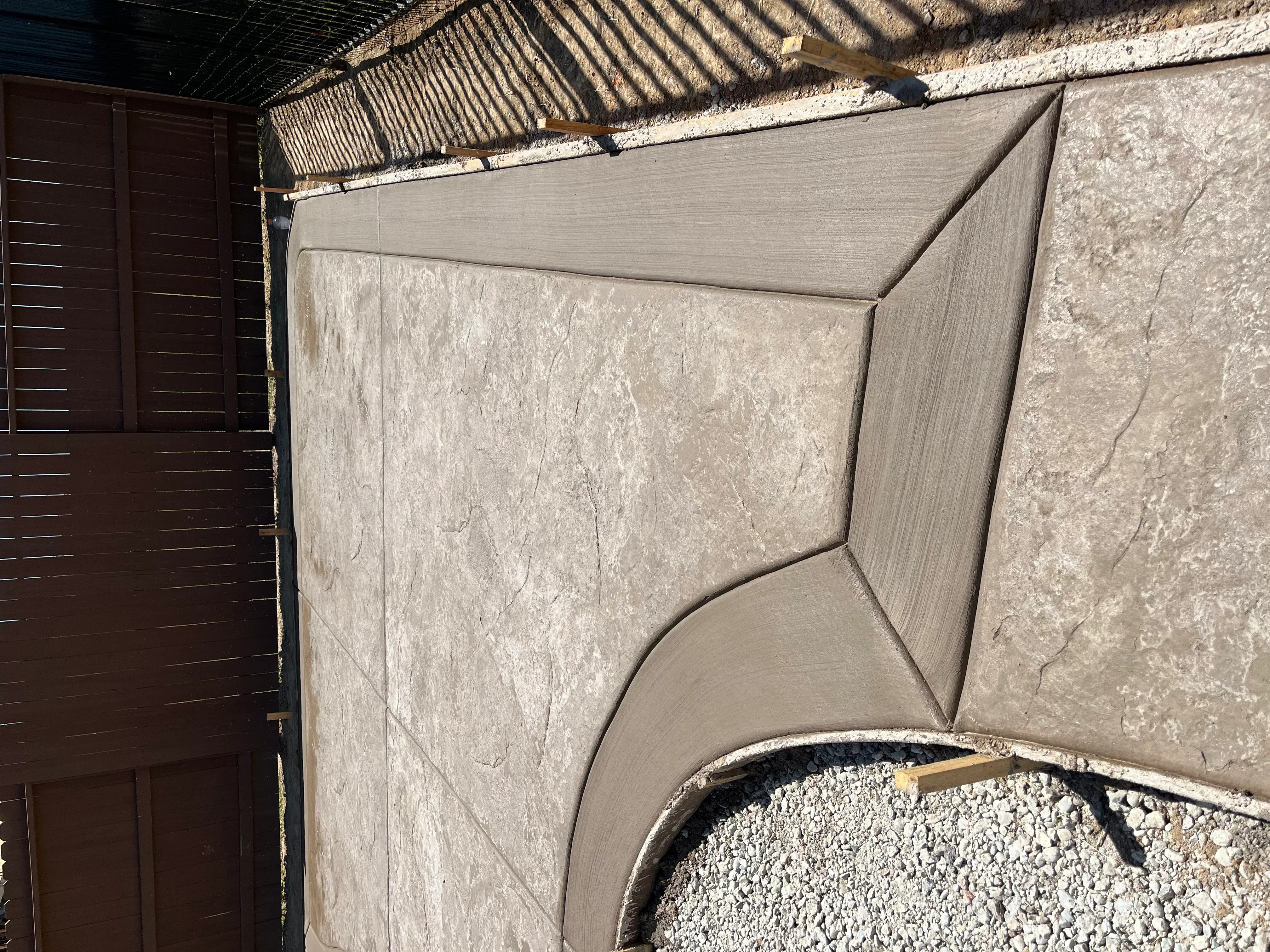 Stamped decorative concrete patio with curved design and pergola overhead in Sacramento