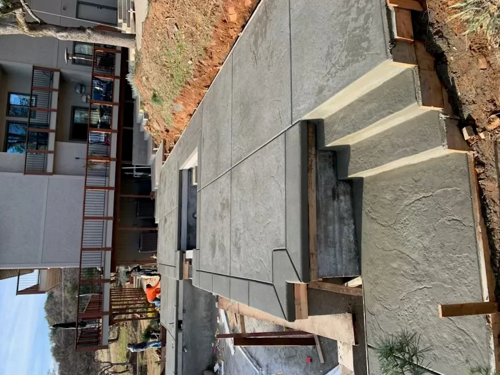 Gray concrete retaining wall with drainage system on hillside property