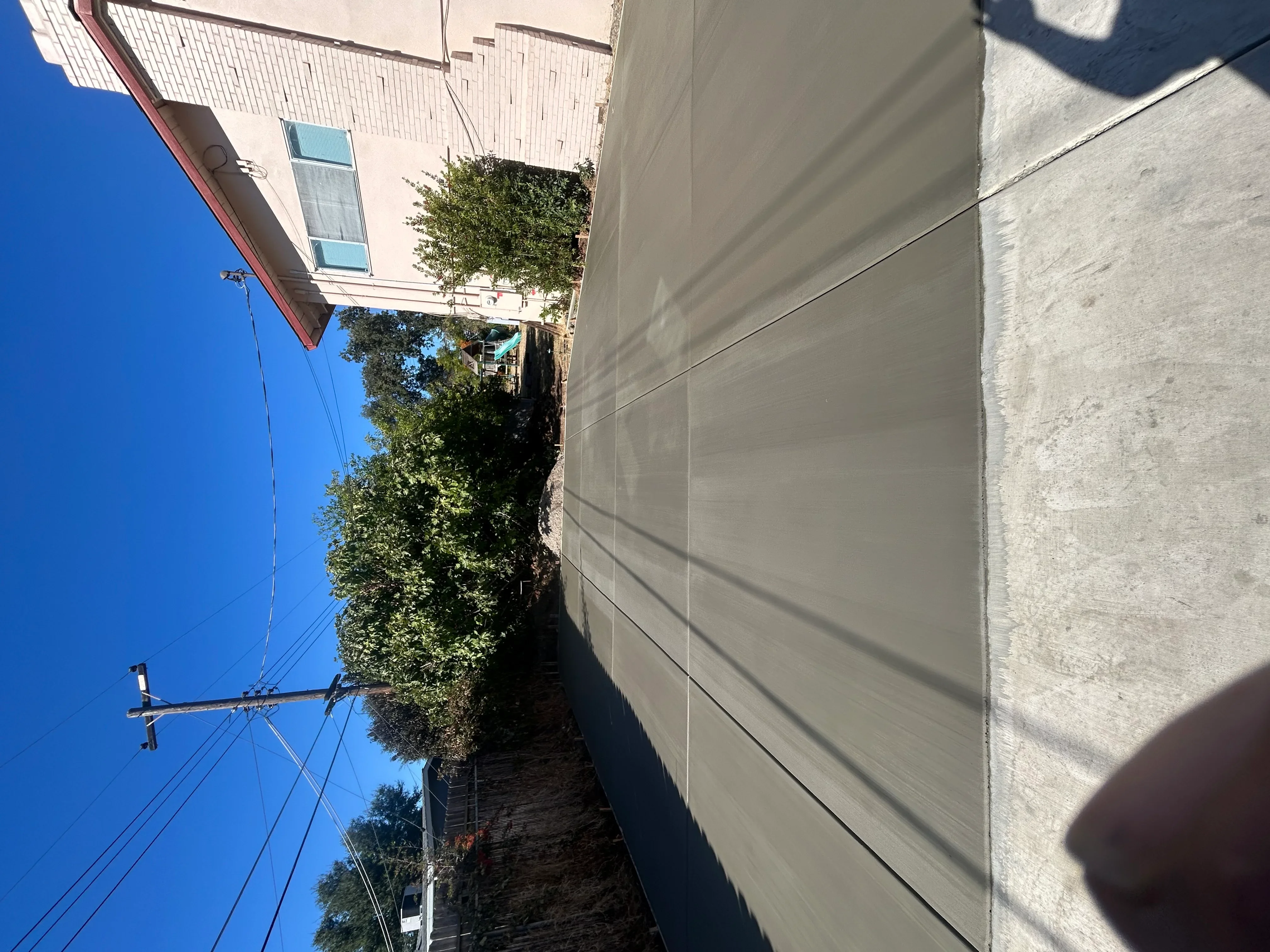 Newly poured concrete driveway with control joints beside residential home