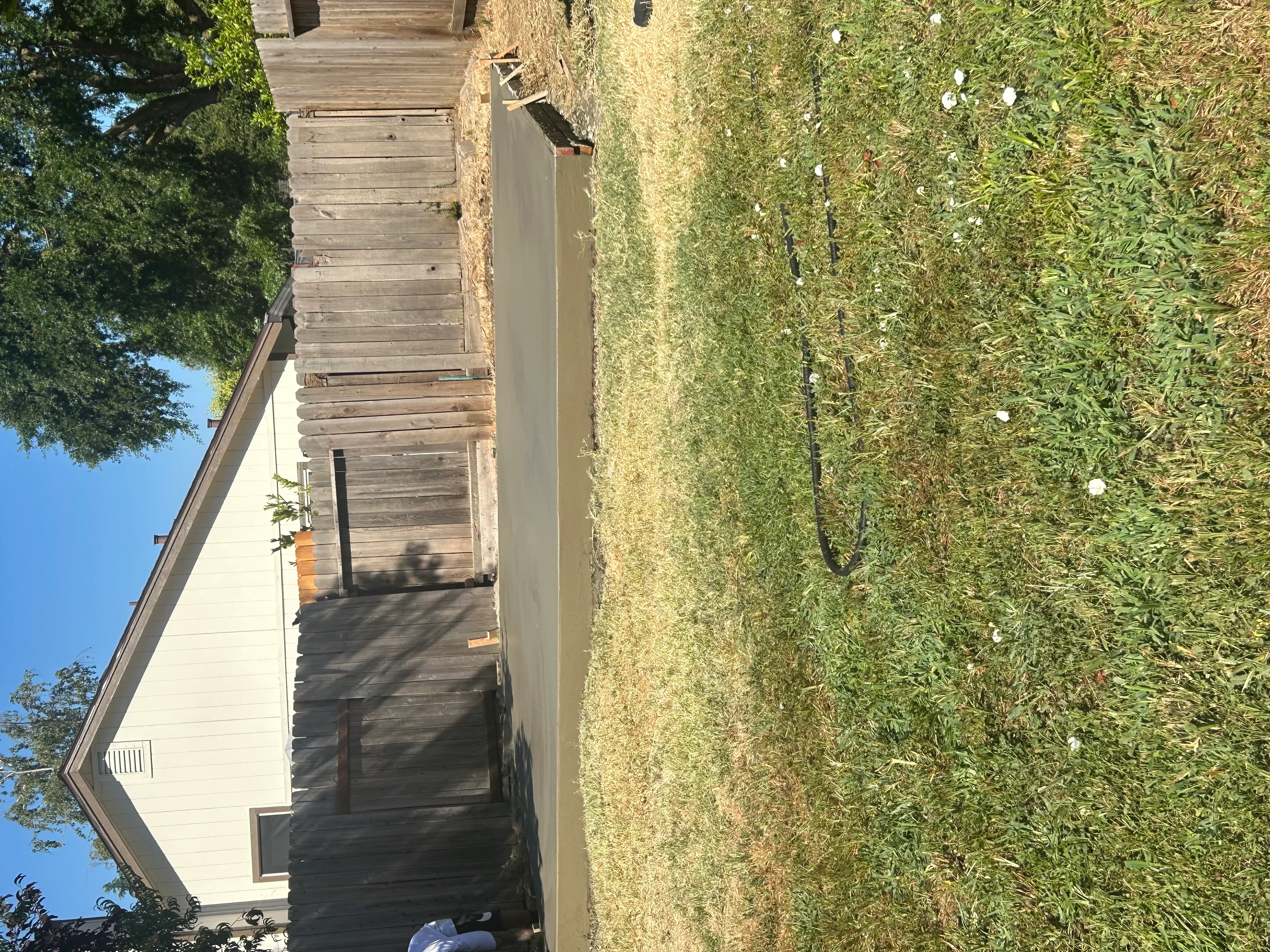 Newly poured concrete driveway alongside residential home with green lawn