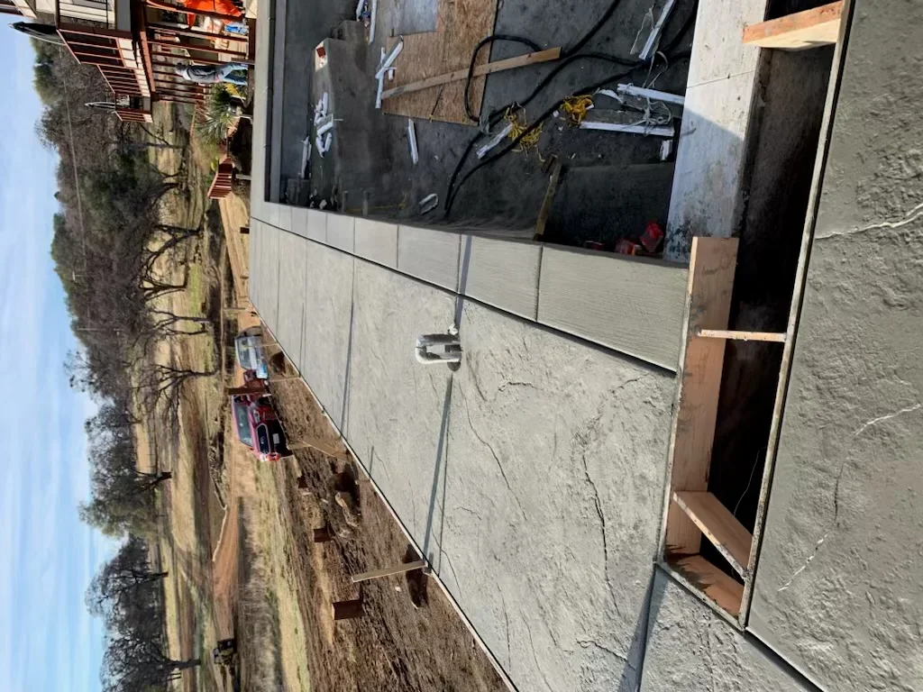Newly poured concrete stem wall and foundation with formed edges and drainage setup