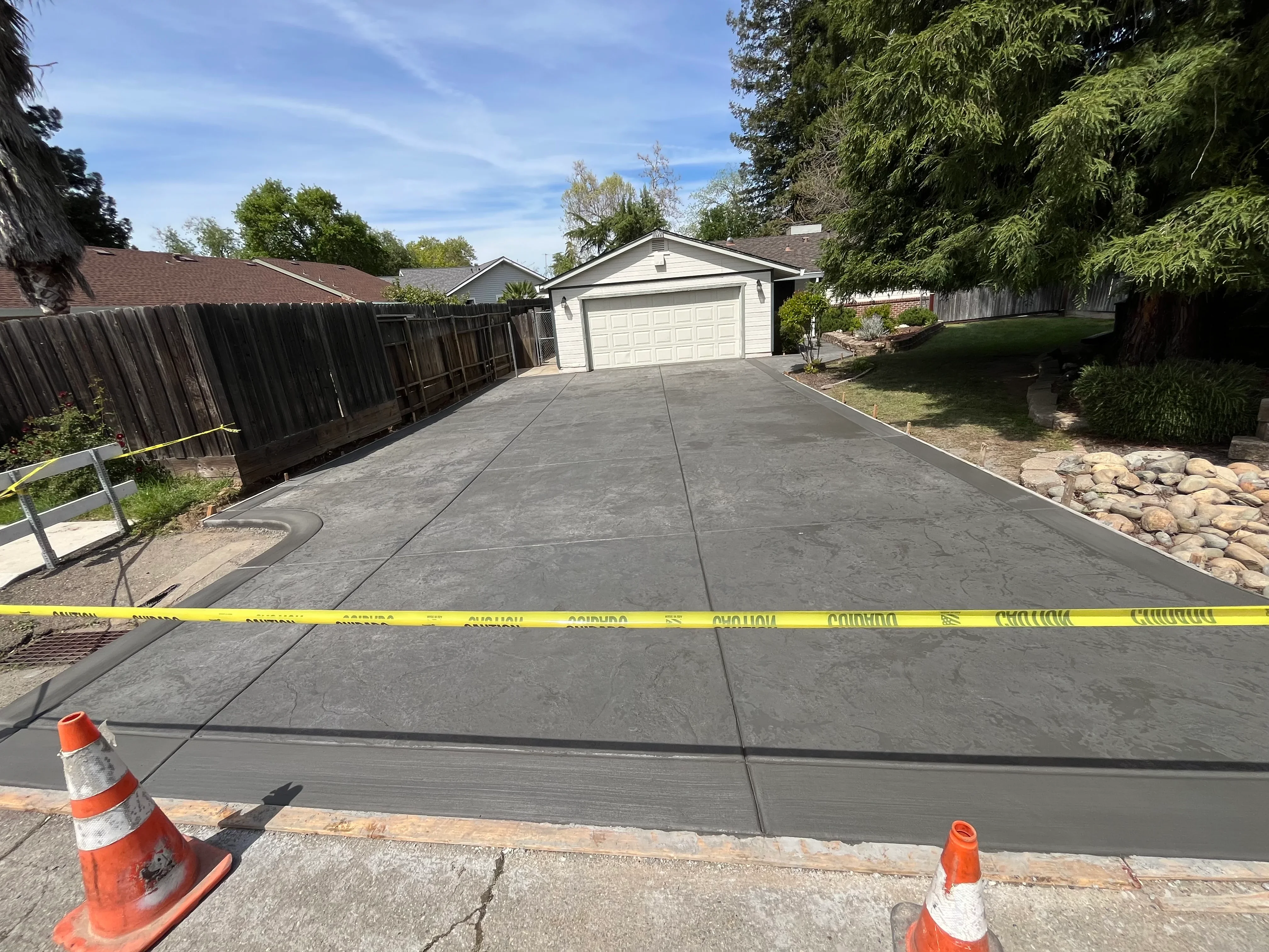 New gray concrete driveway with control joints leading to white two-car garage