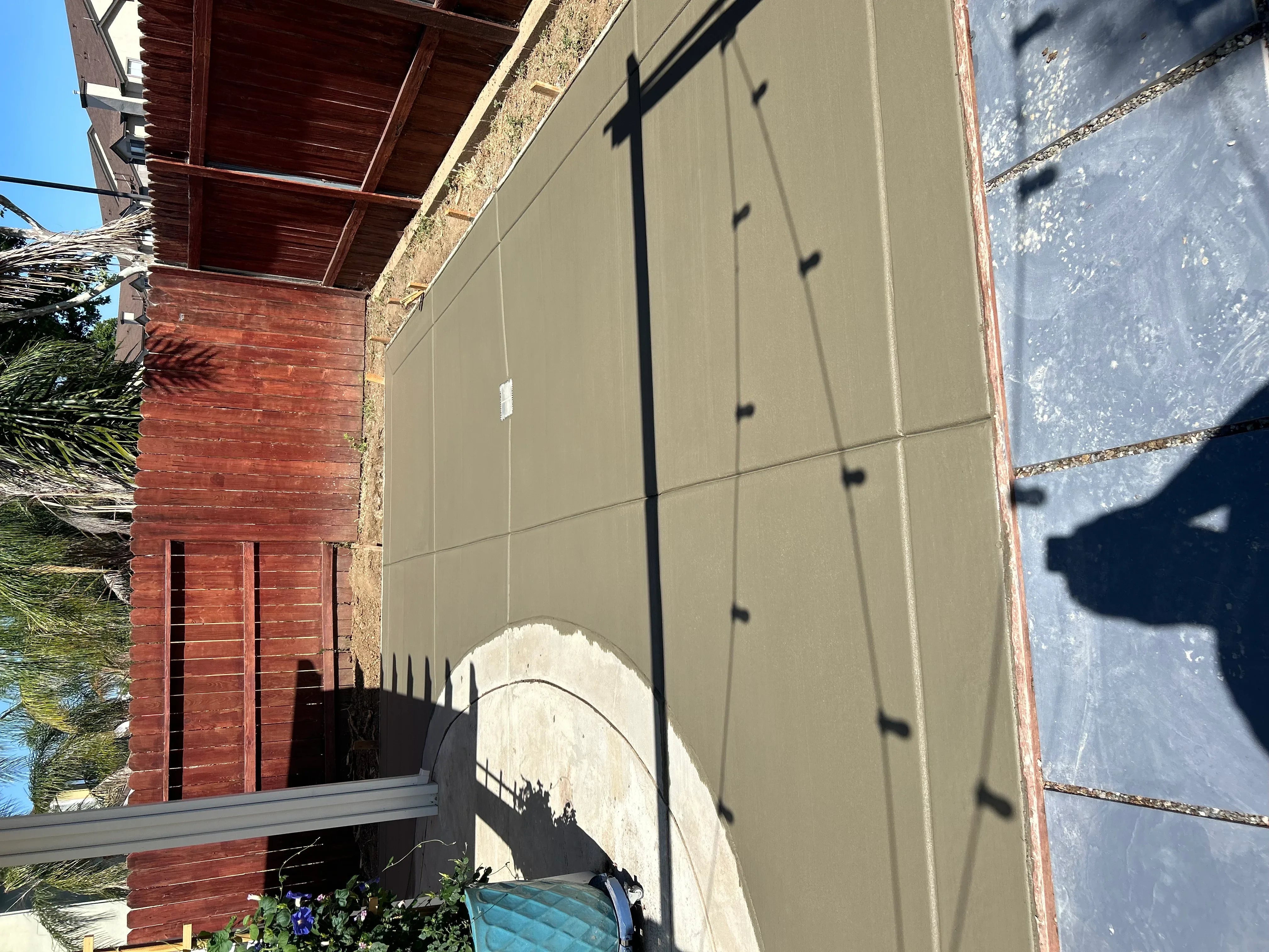 Finished concrete wall panels with control joints and grid pattern installed against brick structure
